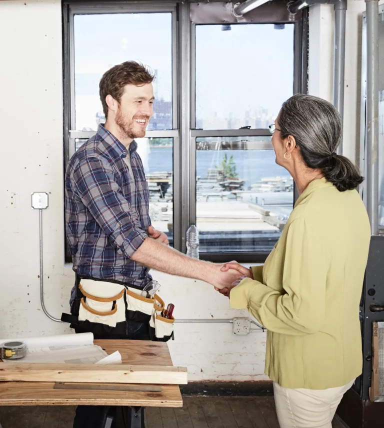 Artisan et cliente se serrant la main devant une fenêtre